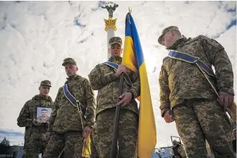  ?? VADIM GHIRDA, AP ?? Ukrainian servicemen walk ahead of the coffin and carry a photograph of their fallen colleague, Vadym Popelniuk, during a religious service in Kyiv on Friday.