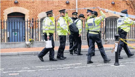  ?? PETER NICHOLLS • REUTERS ?? Police officers cross the cordon at the scene of multiple stabbings in Reading, Britain, Sunday.