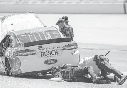  ?? BUTCH DILL/AP ?? Crew members for NASCAR driver Kevin Harvick inspect the car after he ran over some debris on his first qualifying lap caused by his teammate Aric Almirola crashing during qualifying for the GEICO 500 auto race at Talladega Superspeed­way on Saturday.
