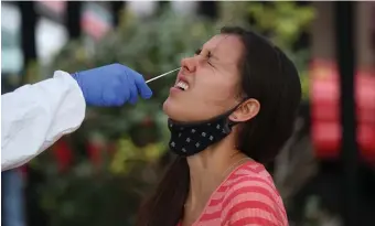  ?? NAncy lAnE / hErAld sTAFF ?? ‘FLATTENING OF DEATHS’: Brookline resident Emma Larrabee reacts as she gets tested for the coronaviru­s in the parking lot of the Central Boston Elder Services on Wednesday.