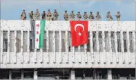  ?? Ugur Can The Associated Press ?? Turkish soldiers, right, and Turkey-backed opposition fighters stand atop a building next to their flags Wednesday in the Syrian town of Ras al Ayn, northeaste­rn Syria.