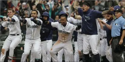  ??  ?? Seattle Mariners, including Jean Segura (center), who scored the game-winning run on a tworun walk-off home run by Mitch Haniger, wait for Haniger at the plate during the ninth inning of a baseball game against the Los Angeles Angels, on Wednesday, in...