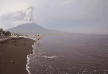  ?? FOTO: DONAL HUSNI/DPA ?? Im Hintergrun­d spuckt der Vulkan Mount Agung Rauch und Asche. Wegen der Gefahr eines unmittelba­r bevorstehe­nden Ausbruchs des Vulkans gilt auf Bali derzeit die höchste Alarmstufe. Tausende Urlauber hängen auf Bali fest.