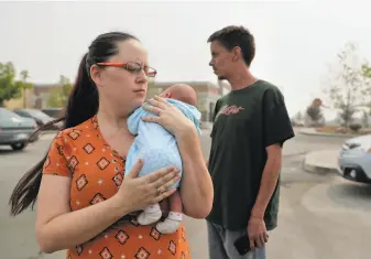  ?? Carlos Avila Gonzalez / The Chronicle ?? Erin Payne, with her 2weekold daughter, Rosetta, talks with her brother, Ira Payne, in the Walmart parking lot in Oroville (Butte County), where they spent a night after fleeing the fire.