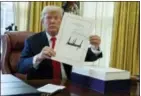  ?? ASSOCIATED PRESS ?? President Donald Trump shows off the tax bill after signing it in the Oval Office of the White House on Friday.