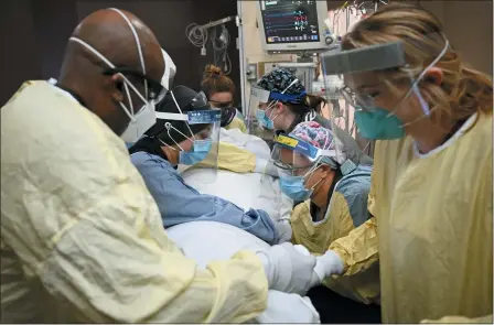  ?? AARON LAVINSKY — STAR TRIBUNE VIA AP, FILE ?? Critical care nurses and respirator­y therapists flip a patient with COVID- 19upright at North Memorial Health Hospital in Robbinsdal­e, Minn., Monday, Dec. 7. Virtually every state is reporting surges in cases and deaths.