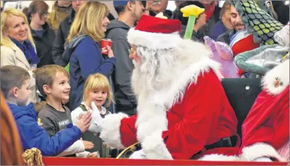  ??  ?? Santa greets some parade goers who were particular­ly eager to get his attention.