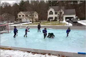  ?? Iron Sleek photo via Associated Press ?? This Jan. 17, 2016 photo provided by Iron Sleek shows children playing hockey on a rink in the frontyard of a residentia­l area and built with an Iron Sleek rink kit in Wilton, N.Y.