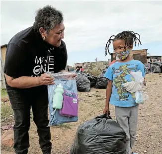  ?? Picture: WERNER HILLS ?? HARD WORK: Move One Million field representa­tive Merlene Alexander hands over a school bag filled with stationery, a lunchbox and cooldrink bottle to Leandrio Grootboom, 6, in Windvogel