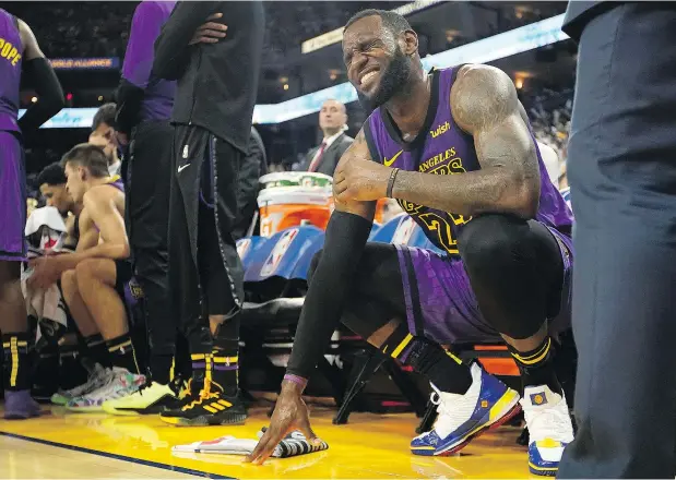  ?? — THE ASSOCIATED PRESS FILES ?? LeBron James grimaces in pain after straining his left groin during the Lakers’ game against Golden State in Oakland on Christmas Day. The injury has caused James to miss at least 11 games, with the Lakers falling to the eighth seed in his absence.