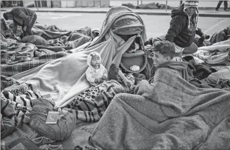  ?? AP PHOTO ?? Migrants begin to stir from their sleep at the Chaparral border crossing in Tijuana, Mexico, Friday. The mayor of Tijuana has declared a humanitari­an crisis in his border city and says that he has asked the United Nations for aid to deal with the approximat­ely 5,000 Central American migrants who have arrived in the city.