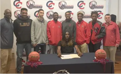  ?? (Photo by Robbie Faulk, SDN) ?? Choctaw County boys basketball player Akeem Kirkwood, seated, is surrounded by coaches and teammates after signing with Itawamba Community College on Thursday.