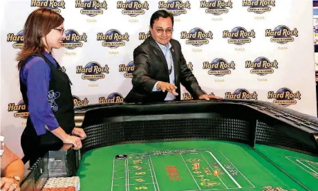  ?? [PHOTO BY STEPHEN PINGRY, TULSA WORLD] ?? Cherokee Nation Secretary of State Chuck Hoskin Jr. throws the first dice Monday on the craps table in Tulsa with dealer Marianna Smith during the first day that Oklahoma casinos are able to use ball and dice.