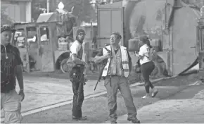  ?? MARK HOFFMAN / MILWAUKEE JOURNAL SENTINEL ?? A pair of men carrying assault-style rifles mingle Tuesday near the Kenosha County Courthouse in Kenosha.