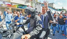  ?? (AFP) ?? Venezuela’s National Assembly head and the country’s self-proclaimed ‘acting president’ Juan Guaido (back of motorbike), at Bolivar Square in Chacao, eastern Caracas, on Friday