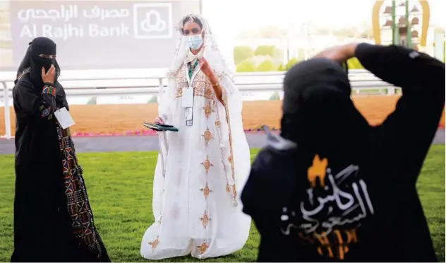  ?? Associated Press ?? ↑ Television presenter Haifa Almami, wearing a traditiona­l attire, poses for a photograph­er in Riyadh on Friday.