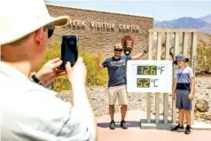  ?? ROGER KISBY/THE NEW YORK TIMES ?? Visitors take photos in front of the thermomete­r at the visitors center in Furnace Creek at Death Valley National Park in Death Valley, Calif., on Saturday.