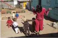  ??  ?? Unos niños buscan en los bolsillos de una visitante a un jardín de infancia de Soweto.