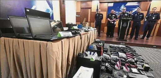  ??  ?? Fraudulent use: Mazlan Lazim (centre) briefing the media during a press conference at the KL police contingent HQ on the items seized from the Macau Scam syndicate.