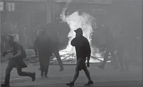  ?? MATTHIAS SCHRADER/AP PHOTO ?? Demonstrat­ors walk past a fire Friday during a protest against the G-20 summit in Hamburg, northern Germany.