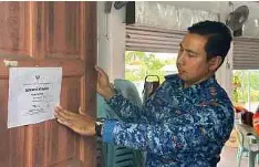  ?? ?? PETUGAS meletakkan notis penutupan PPS Dewan Entingan di Samarahan.