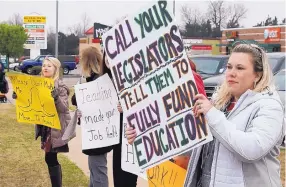  ?? SUE OGROCKI/ASSOCIATED PRESS ?? Teacher Adrien Gates pickets with other educators on a street corner in Norman, Okla., on Tuesday. Teachers plan to strike on Monday, seeking a $10,000 per year raise.