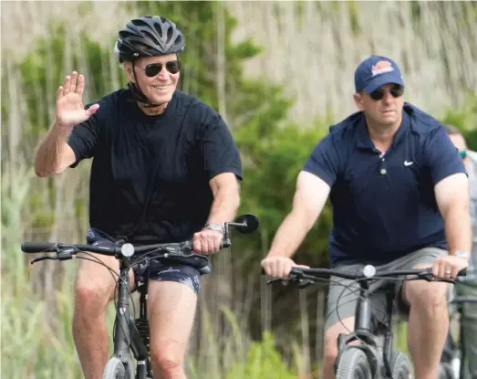  ?? AP ?? President Joe Biden rides his bike on a bike path at Gordon’s Pond in Rehoboth Beach, Delaware.