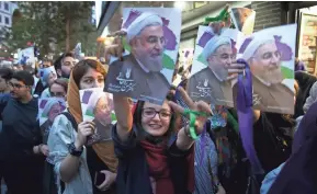  ?? ASSOCIATED PRESS ?? A supporter of Iranian President Hassan Rouhani holds his poster and flashes a victory sign while celebratin­g Rouhani’s win in the presidenti­al election in Tehran, Iran, on Saturday.
