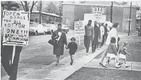  ??  ?? In this 1964 archive photo, a Black woman and boy march among protesters outside Noah Webster Elementary School in Hartford. Signs denounce neighborho­od school zones that created racial segregatio­n.