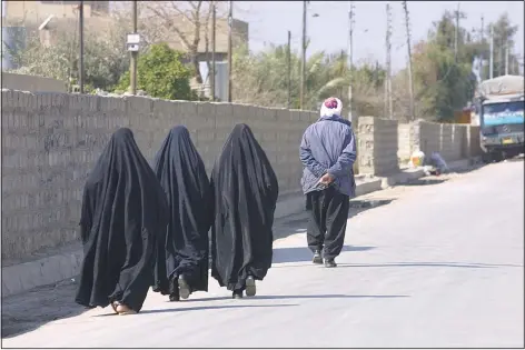  ?? (AP/Murat Duzyol) ?? Three women walk behind a man in February 2003 in Erbil, Iraq. A version of this original image was manipulate­d to digitally add chains on the women’s ankles, with a caption erroneousl­y claiming it was made in Afghanista­n after the Taliban took control of the country this month.