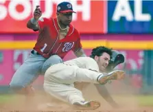  ?? THE ASSOCIATED PRESS ?? With the Washington Nationals’ Wilmer Difo covering second base in the ninth inning of Sunday’s game in Atlanta, the Braves’ Dansby Swanson slides in for a double. Swanson was called out, but a review overturned the call and he scored when Charlie...