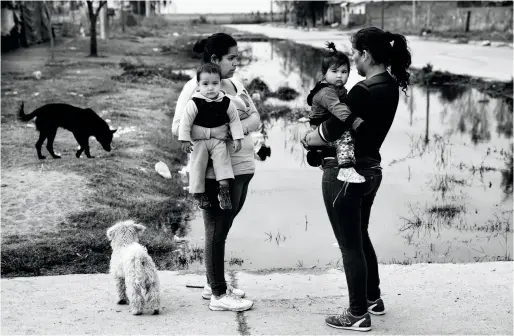  ??  ?? Dans le quartier Eva Perón, à San Luis, Jimena Robira et Carina Soto passent leurs journées à empêcher leurs enfants d’aller jouer dans l’eau poisseuse qui remonte partout. Une odeur pestilenti­elle enveloppe l’endroit.