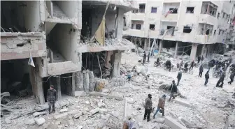  ??  ?? Syrians inspect the remnants of buildings destroyed by missile strikes in Douma, eastern Ghouta.