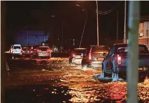  ?? NSTP PIC BY ADAM ARININ ?? Cars driving through a flooded road in Putatan, Sabah, on Saturday.