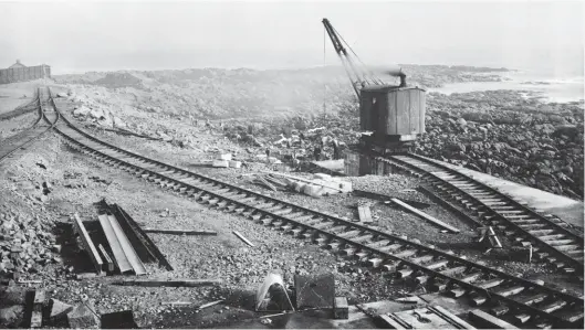  ??  ?? Early days at the north end of the North Breakwater scheme, probably pre-1914, with a small steam crane assisting in the movement of material and rocks in preparatio­n for the main constructi­on work to begin. The pointwork trailing in from the left is from the Harbour of Refuge Works (North Depot), which claimed new ground beside Pleasure Walk and rounded the southern side of North Inch to a point near the south pier of Peterhead harbour. In 1910 it was decided to conclude the South Breakwater at 2,850ft (rather than the envisaged 3,250ft) and use the surplus rubble as foundation for an 80ft roundel that would house a lighthouse. In due course the plans for the North Breakwater were also changed, a new alignment offering greater shelter and use of a rocky outcrop. Also, rubble was not used – the South Breakwater was observed suffering subsidence – and so instead the rocky base of the North Breakwater was given a solid concrete foundation, and shear checks were also deemed necessary. Maud Railway Museum Collection