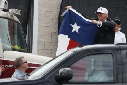  ?? EVAN VUCCI — THE ASSOCIATED PRESS ?? President Donald Trump, accompanie­d by first lady Melania Trump, holds up a Texas flag after speaking with supporters outside Firehouse 5 in Corpus Christi, Texas, Tuesday, Aug. 29, following a briefing on Harvey relief efforts.