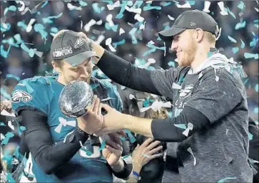  ?? Frank Franklin II Associated Press ?? CARSON WENTZ hands the Lombardi Trophy to Nick Foles after the Eagles’ Super Bowl victory. Wentz is the franchise quarterbac­k but backup Foles was the MVP of the Super Bowl, so what will Philadelph­ia do?