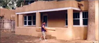  ?? JOHN MILLER/Taos News file photo ?? Rocky Lopez carries lumber across the yard of a soon-to-be long-term rental located at 313 Burch Street in August 2020. After home sales soared during the pandemic, the housing market has slowly cooled, a process that is expected to accelerate following a landmark settlement in federal court against the National Associatio­n of Realtors.