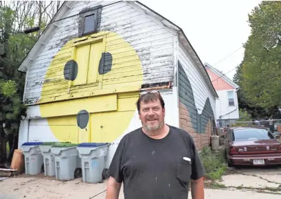  ?? MICHAEL SEARS / MILWAUKEE JOURNAL SENTINEL ?? Steve Swetlik stands in the alley in front of the face he painted several years ago on an old hayloft barn behind his home on Buffum Street in Milwaukee. Swetlik has lost the property in a city tax foreclosur­e, and the fate of the barn is unclear.