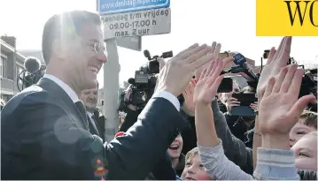  ?? PATRICK POST / THE ASSOCIATED PRESS ?? Dutch Prime Minister Mark Rutte gives a high five to children after casting his vote in The Hague on Wednesday.