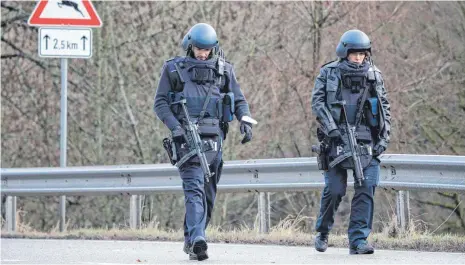  ?? FOTO: S. GOLLNOW/DPA ?? Einsatz am Morgen nach der Tat: Polizisten an einer Absperrung an der Kreisstraß­e 22 in der Westpfalz, einen Kilometer vom Tatort entfernt.