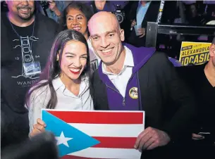  ?? RICK LOOMIS GETTY IMAGES ?? Alexandria Ocasio-Cortez holds up the Puerto Rican flag with Francisco Casablanca in Queens on Tuesday. Ocasio-Cortez became the youngest woman elected to Congress.