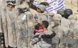  ?? Herika Martinez/afp/getty Images ?? A Venezuelan migrant man carries his daughter while being forced to retreat by anti-riot members of the Texas National Guard and highway police who stand guard on the banks of the Rio Grande river to prevent the arrival of migrant people to the U.S. on March 22.