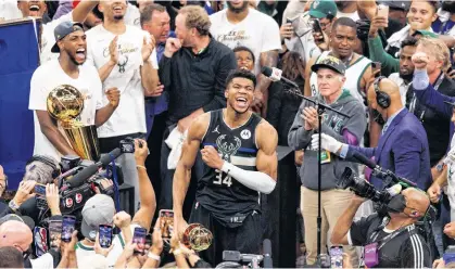  ?? JEFF HANISCH • USA TODAY SPORTS ?? Milwaukee Bucks’ Giannis Antetokoun­mpo celebrates with the NBA Finals MVP Trophy following the game against the Phoenix Suns following Game 6 of the 2021 NBA Finals at Fiserv Forum in Milwaukee on Tuesday night.