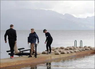  ?? Daily Courier file photo ?? Carter Henry, 17, brother Brock, 13, and their mother, Lori, pile sandbags on the family’s dock on Okanagan Lake in Kelowna to weigh it down as Okanagan Lake rose above its normal level in May.The level of the lake peaked on June 8 at 343.25 metres...