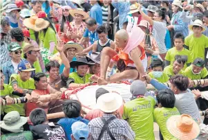  ??  ?? A monk-to-be is shaken up and down on a bamboo stretcher to test his strong determinat­ion to become a monk.