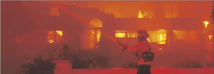  ?? MARCIO J. SANCHEZ/AP ?? A firefighte­r works to put out a structure burning during a wildfire on Wednesday in Laguna Niguel, Calif.