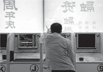  ??  ?? An investor looks at stock price movements on a computer screen at a securities company in Beijing. Chinese stock markets plunged to their lowest in four years yesterday after a global rout. — AFP