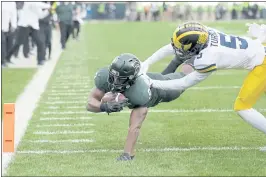  ?? AL GOLDIS — THE ASSOCIATED PRESS ?? Michigan State’s Kenneth Walker, the nation’s rushing leader, dives over the goal line against Michigan’s DJ Turner in the second quarter for one of his five TDs on Saturday.