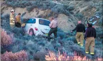  ?? Rick Romancito ?? Taos County Sheriff’s Department officers and Taos Volunteer Fire Department personnel examine a vehicle allegedly driven by Ed Ramsey of Taos that crashed off the southern end of Blueberry Hill Monday (Nov. 19) shortly after 5 p.m. Initial dispatch reports indicated the vehicle was on fire, but no smoke or flames were visible at the scene.